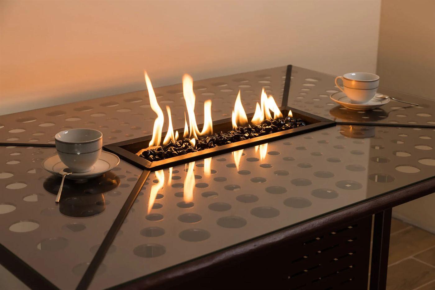 Metal fire table with a perforated top and glass